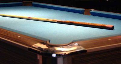 A Billiard table with a wooden cue on it.