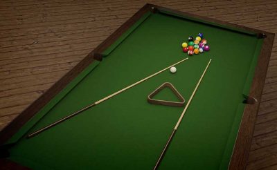 This is a picture of a pool table with two wooden pool cues, balls, and a triangle.